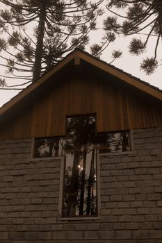 Wooden and stone church facade featuring a cross-shaped window under a forest canopy.
