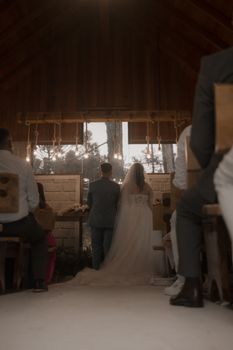 Bride and groom standing in a wooden chapel during an intimate indoor wedding ceremony.