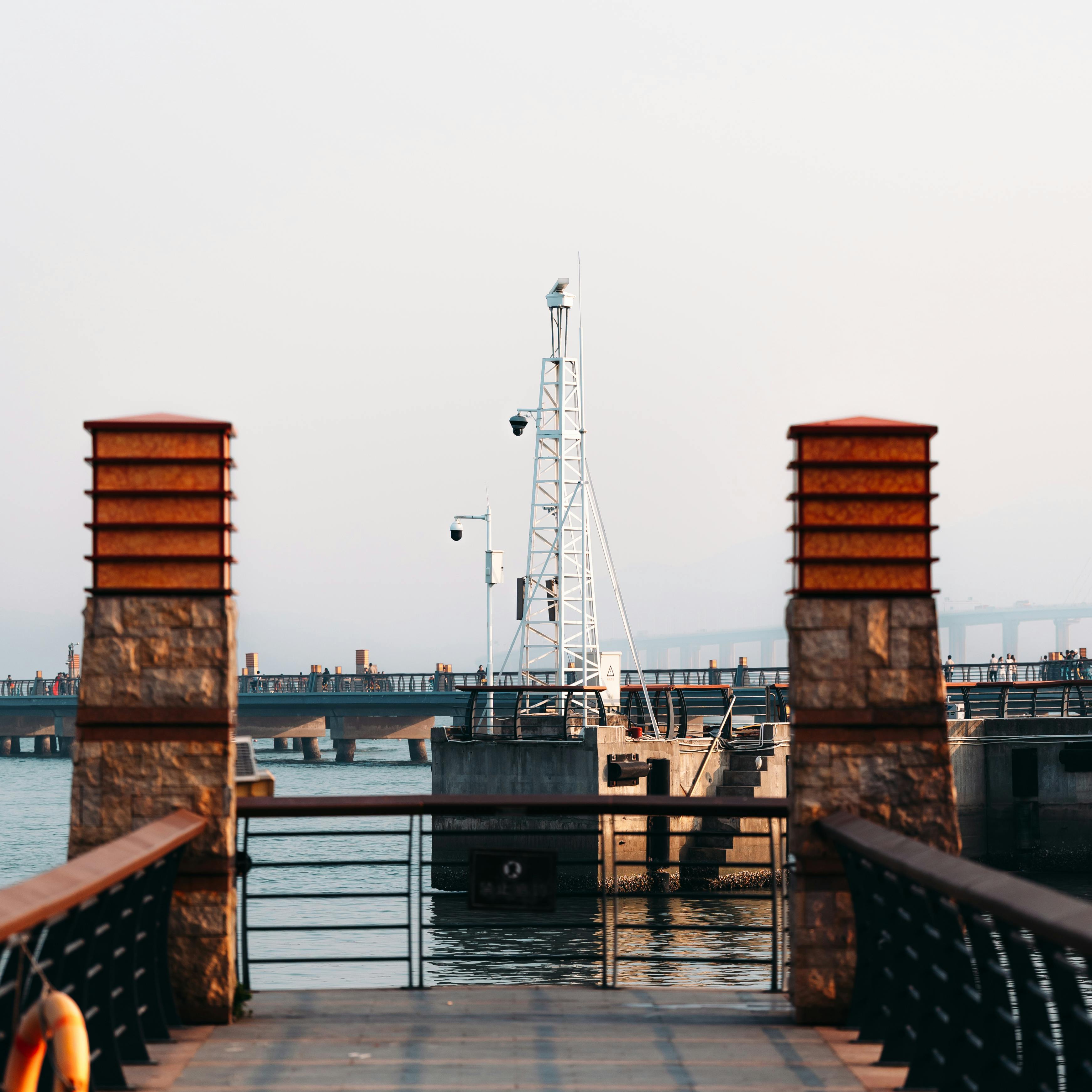A tranquil view from a pier featuring structural elements and calm waters under a clear sky.