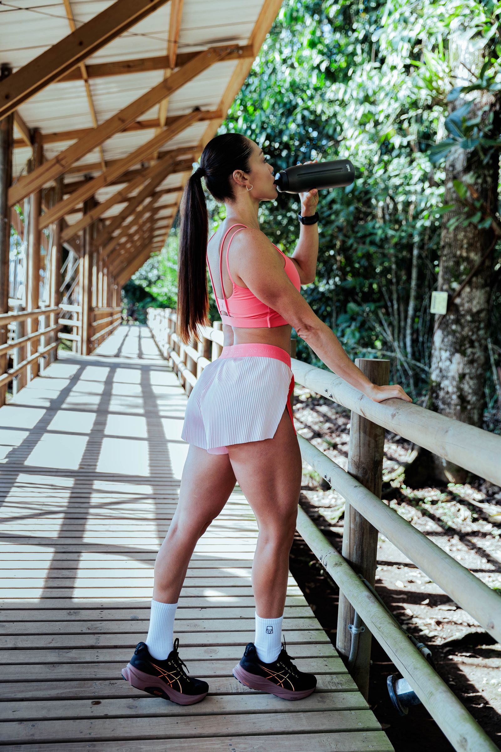 Active woman drinking water outdoors after exercise.