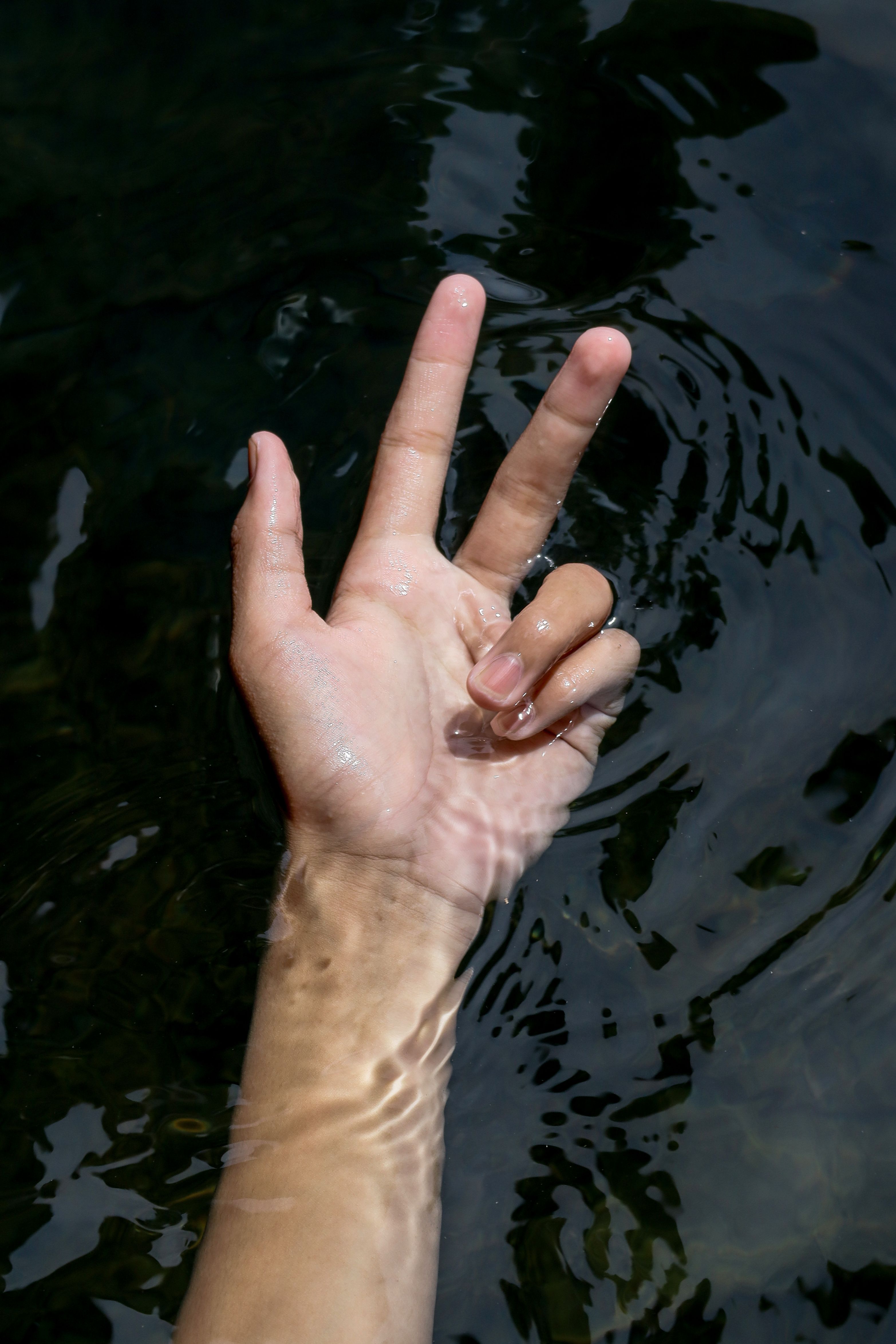 Hand Emerging from Water Displaying Peace Sign · Free Stock Photo