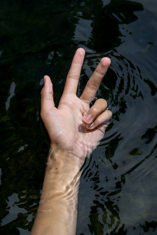 Hand Emerging from Water Displaying Peace Sign · Free Stock Photo