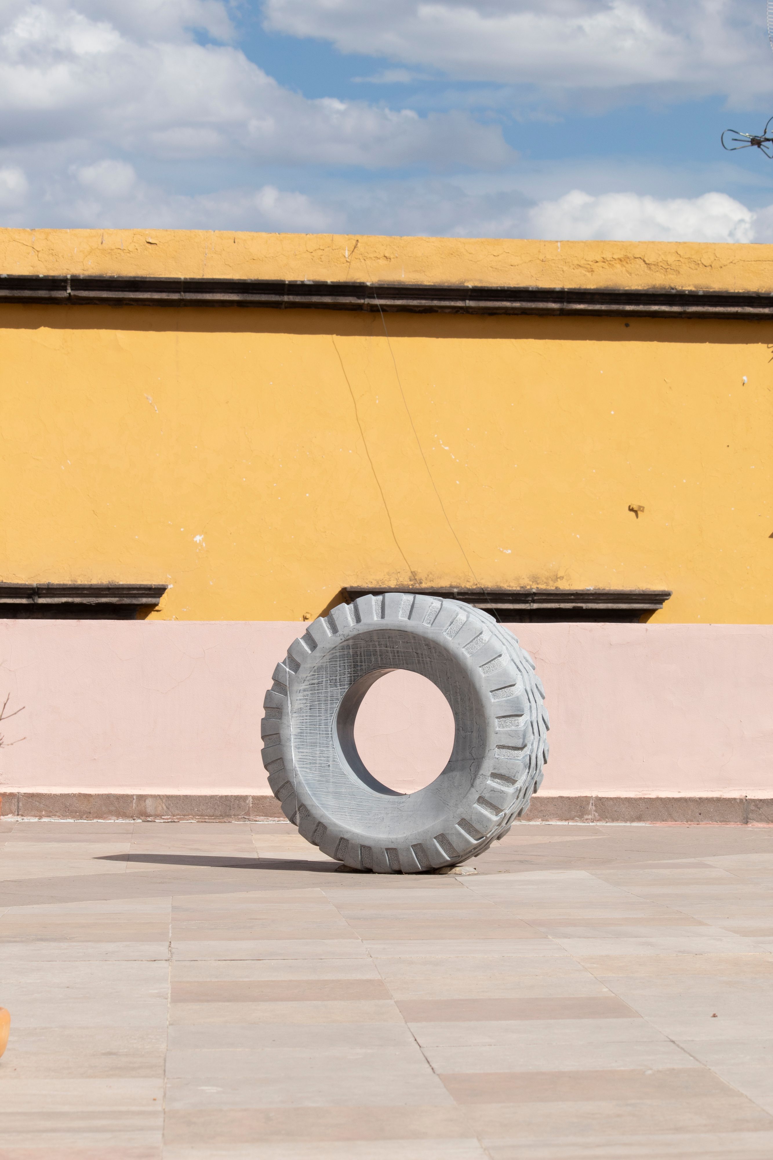 A large tire placed against a colorful wall under the clear sky in San Luis Potosí, Mexico.