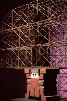 Intricate wire sculpture on a red base with a purple backdrop, showcasing geometry and shadows.