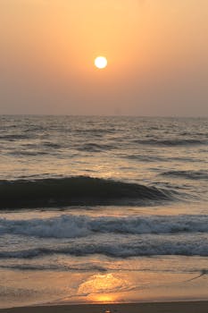 Peaceful beach sunset with waves softly crashing onshore, creating a tranquil evening scene.