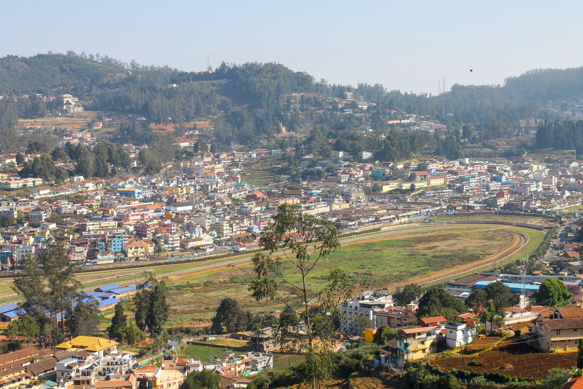 Aerial view of a vibrant city nestled in a lush, mountainous landscape with clear skies.