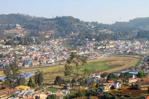 Aerial view of a vibrant city nestled in a lush, mountainous landscape with clear skies.