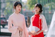 Two Women in Traditional Dresses Holding a Fan