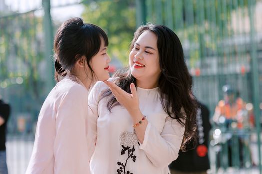 Two smiling women enjoying a bright, sunny day outdoors, sharing a joyful moment.