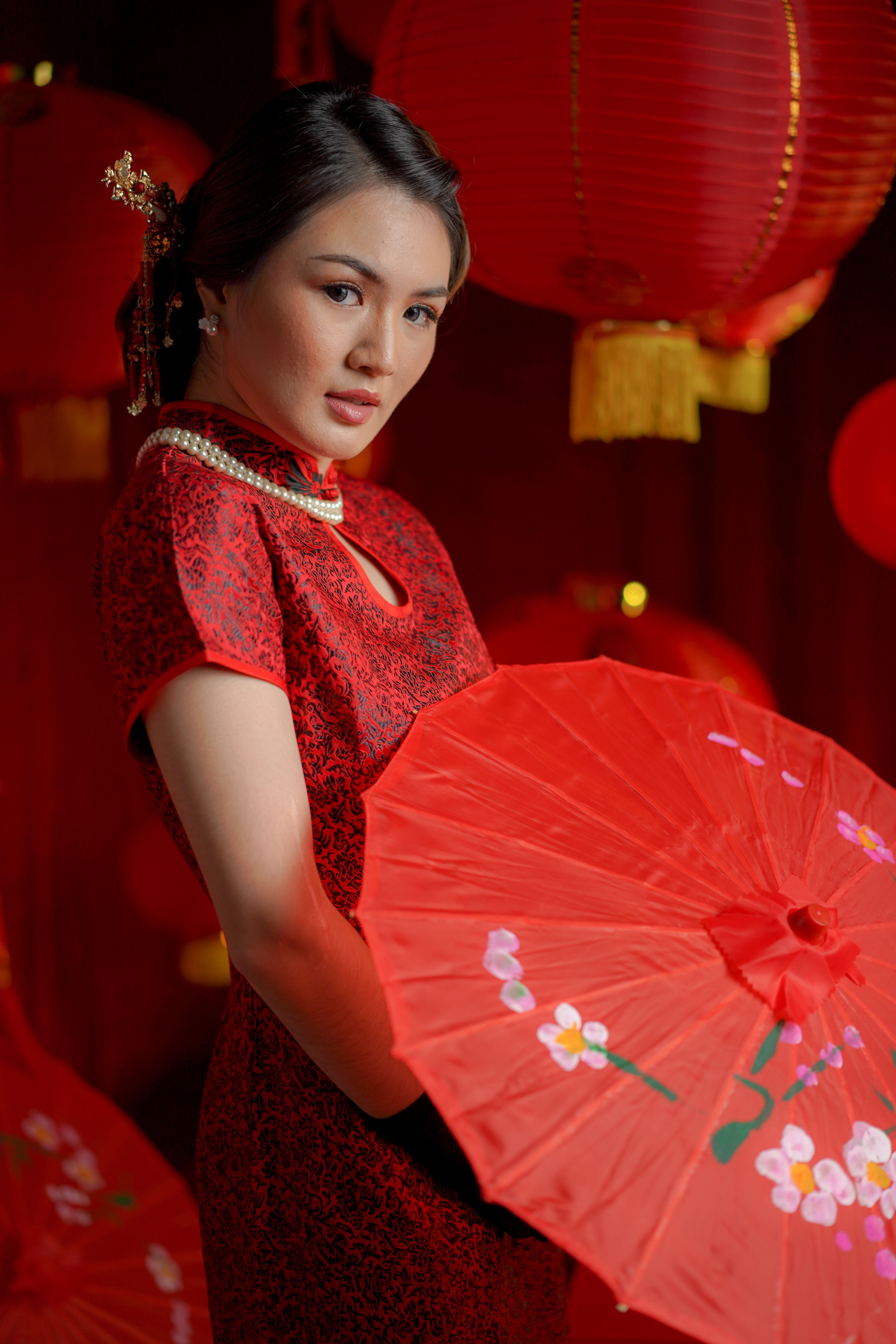 Woman in red traditional dress with parasol and lanterns, perfect for cultural and festive themes.