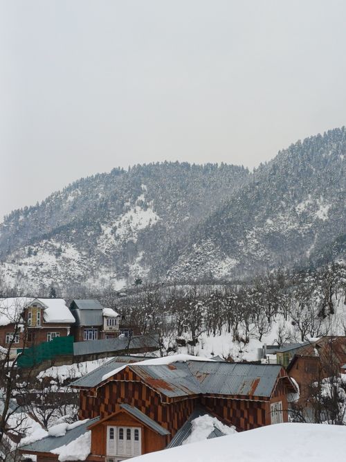 Free Idyllic snow-covered village nestled in the mountains under a winter sky. Stock Photo
