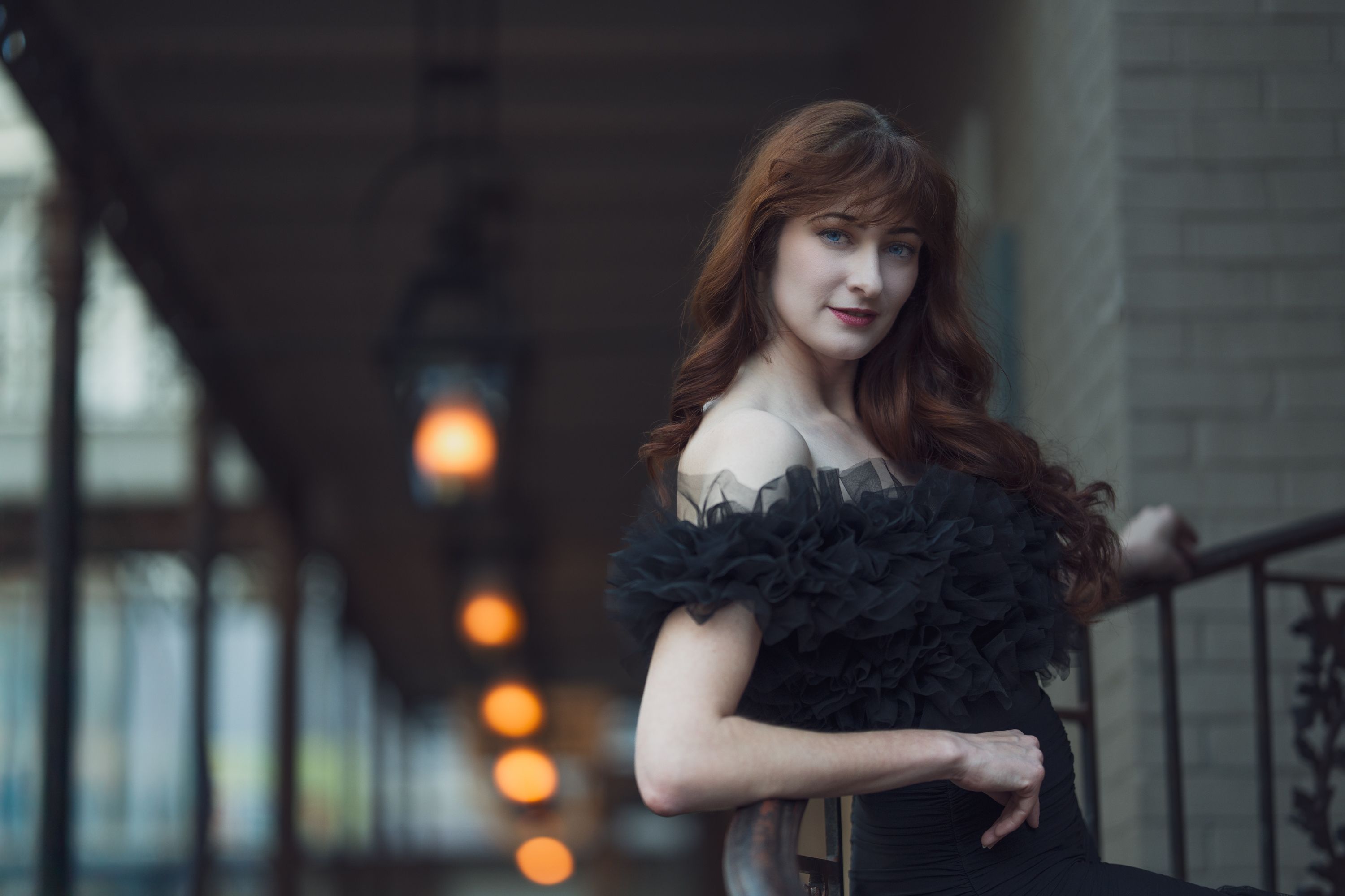 An elegant portrait of a red-haired woman in a black dress on a rooftop at dusk in Nashville, Tennessee.
