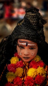 Portrait of a person in vibrant traditional attire with intricate face paint celebrating a cultural festival.