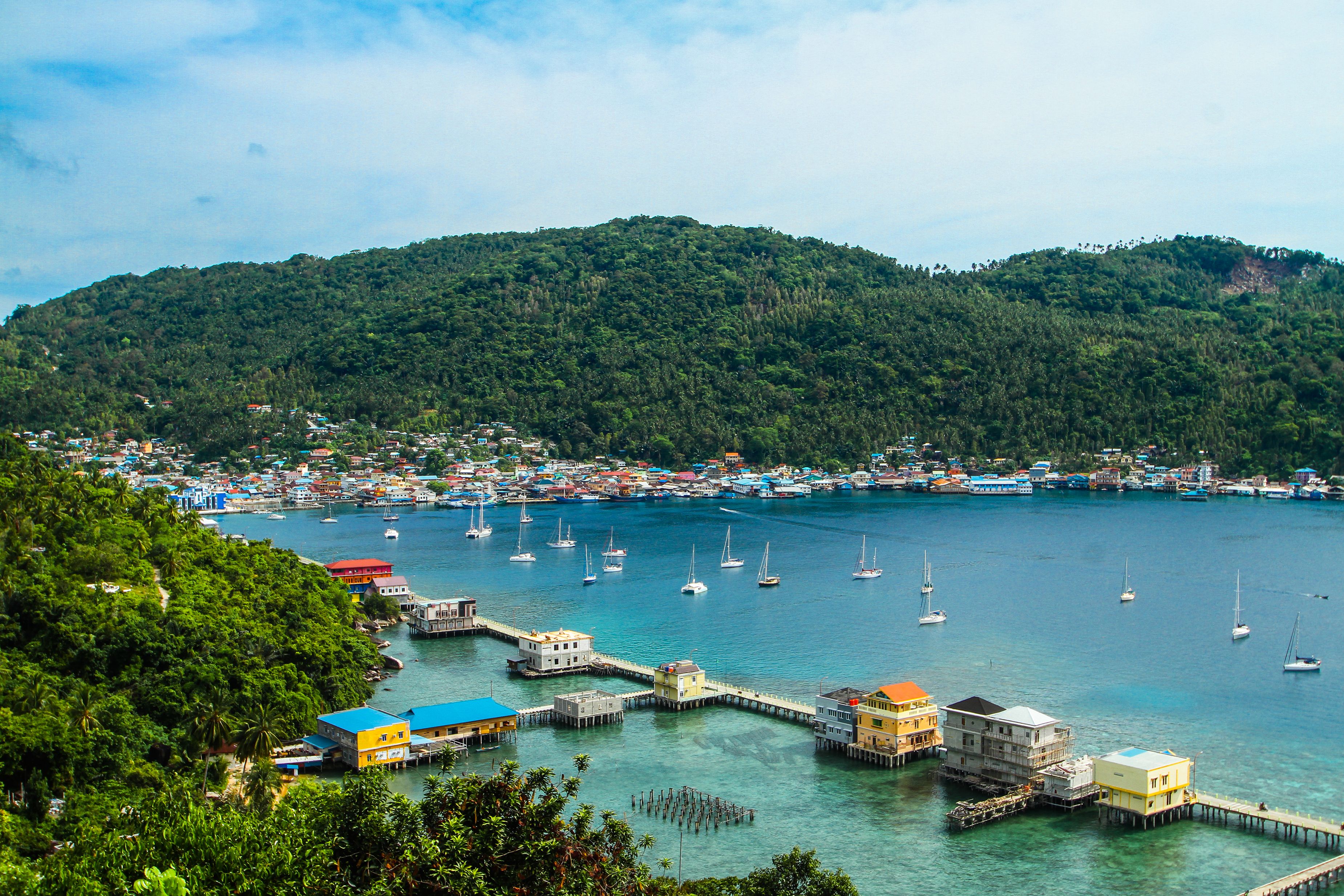 Scenic Coastal Town with Boats and Lush Hills · Free Stock Photo