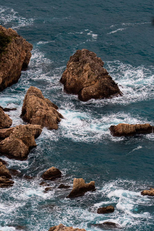 Free Dramatic aerial view of Sicily's rocky coastline with waves crashing against the shore. Stock Photo