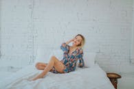 一个穿着花裙的女人在床上放松，靠着白色的砖墙