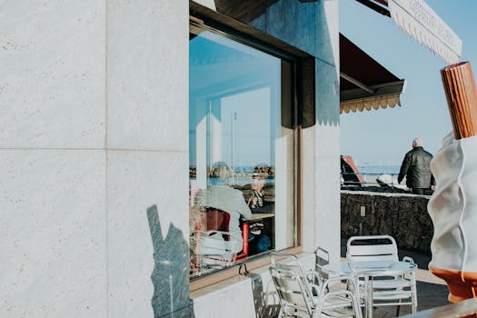 人们在户外咖啡馆里，玻璃窗上映着城市街景