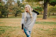 Smiling blonde woman in a poncho enjoying a sunny day at the park.