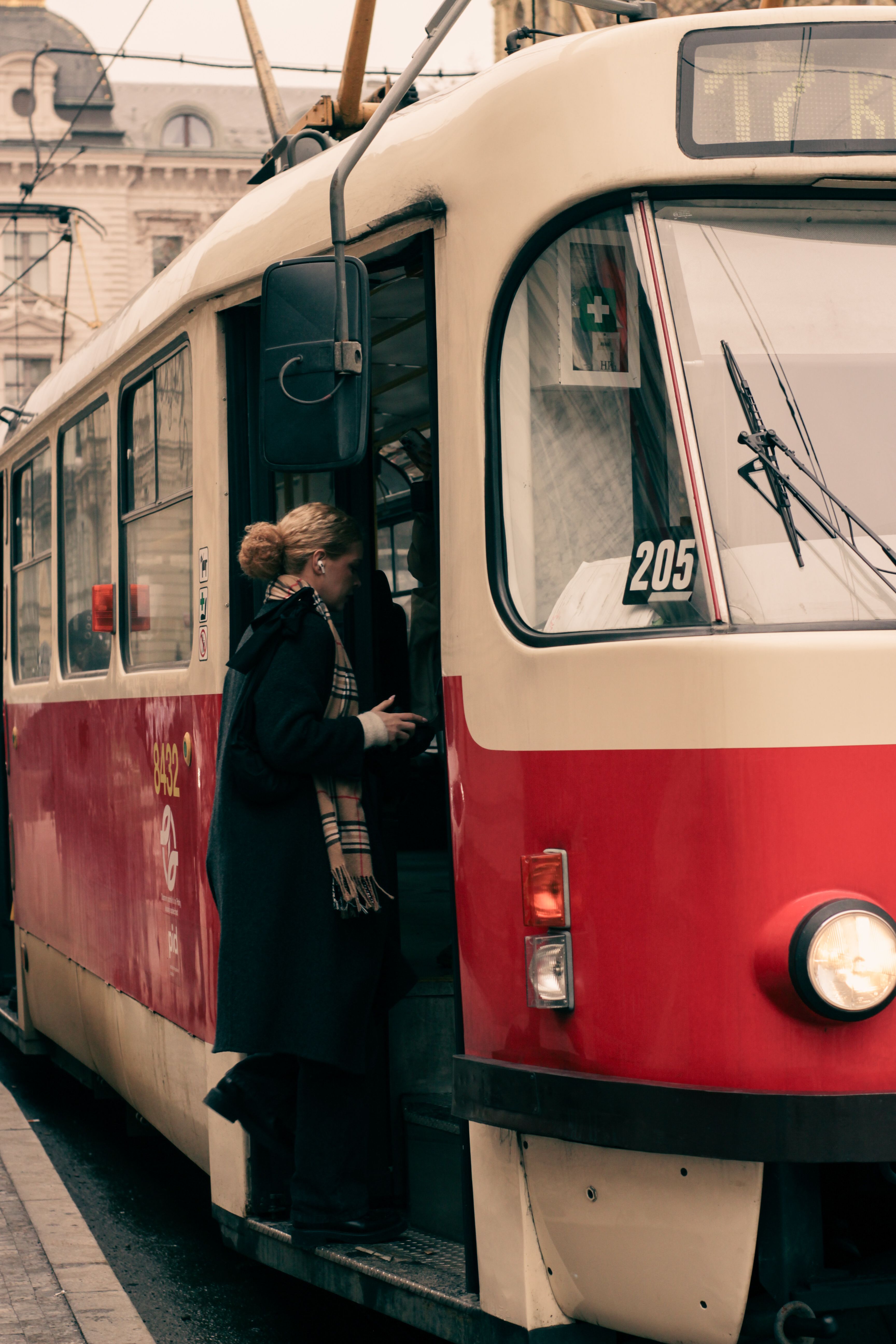 A woman boarding a classic tram in Prague during a crisp autumn day.