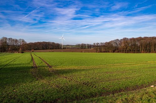 Free Peaceful rural scene in Coesfeld with green fields and a lone wind turbine under a clear blue sky. Stock Photo
