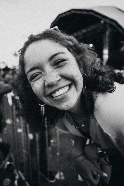 Cheerful black and white portrait of a young woman smiling outdoors at an event.