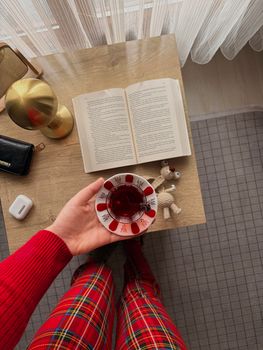 A warm, cozy indoor scene featuring a book, tea, and personal items on a wooden table.