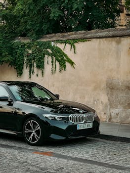 Black luxury car parked by a historic wall in Toledo, Spain. Vibrant summer foliage backdrop.
