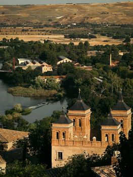 A picturesque view of Toledo's historic architecture amidst lush greenery and a serene river.