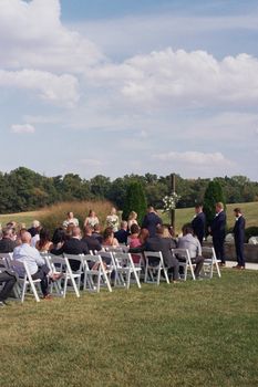 An outdoor wedding ceremony with guests seated on a sunny day.