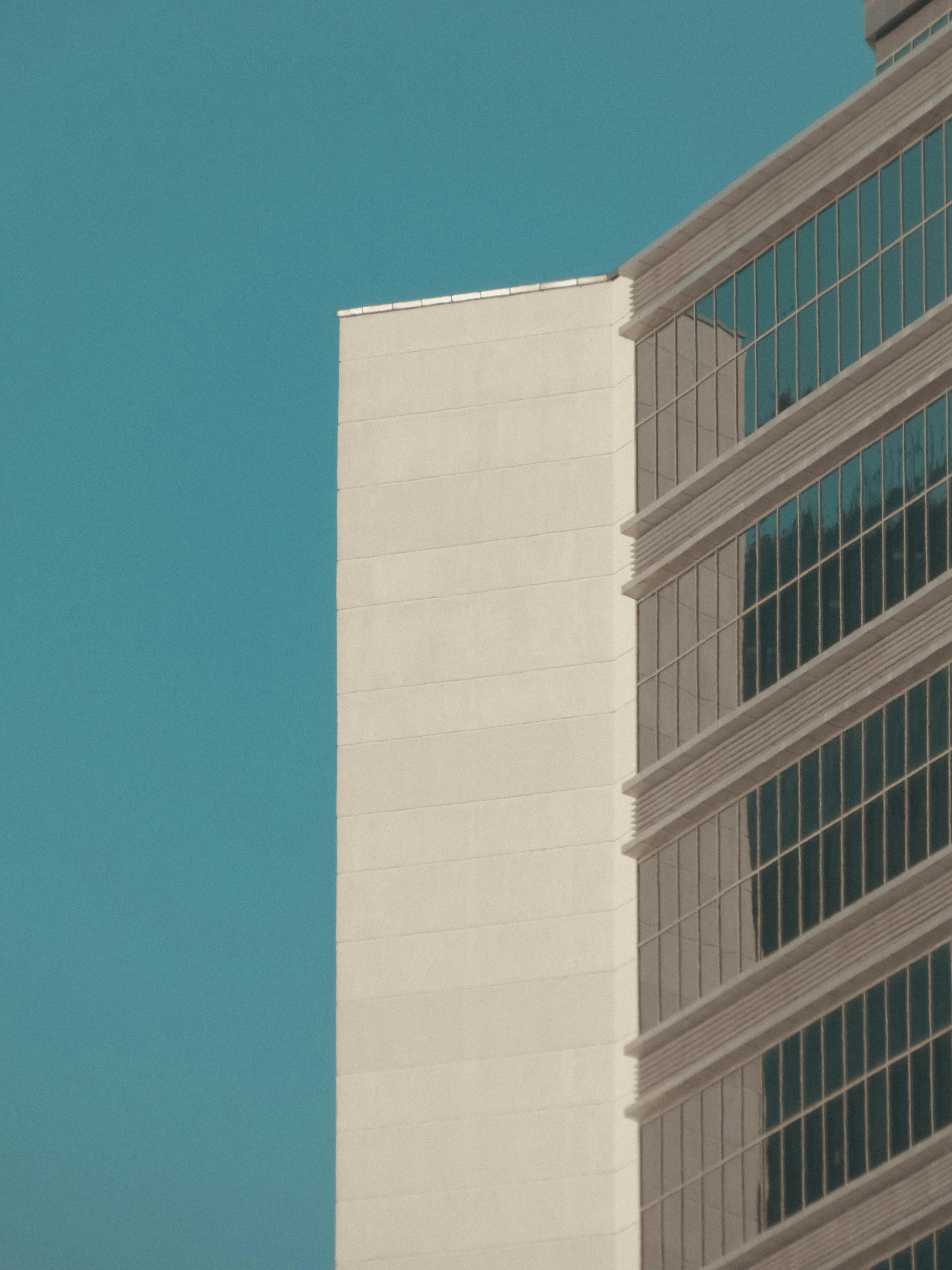 grátis Uma fotografia minimalista da fachada de um edifício moderno contra um céu azul claro. Foto profissional