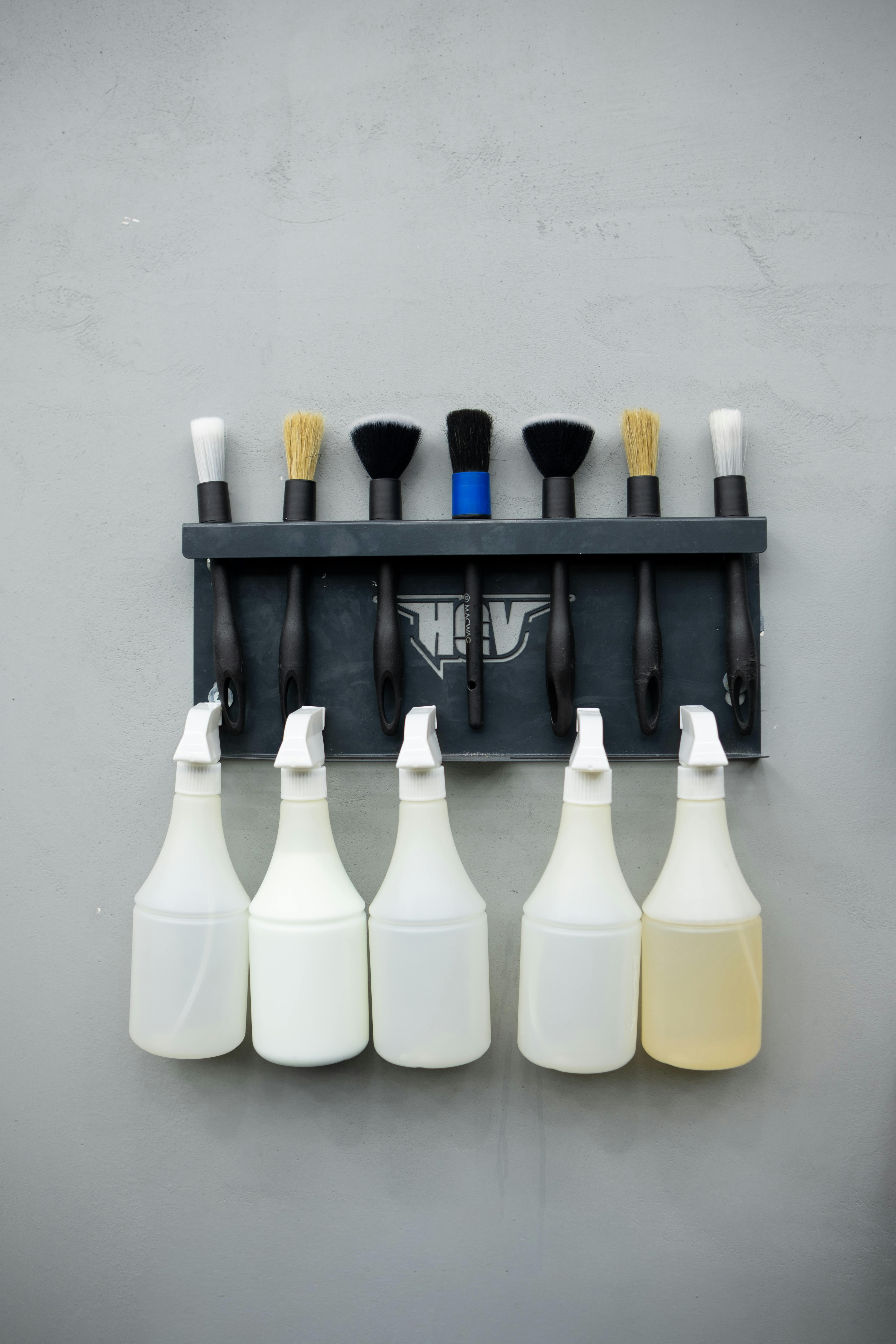 Wall-mounted rack with cleaning brushes and spray bottles. Perfect for organization themes.