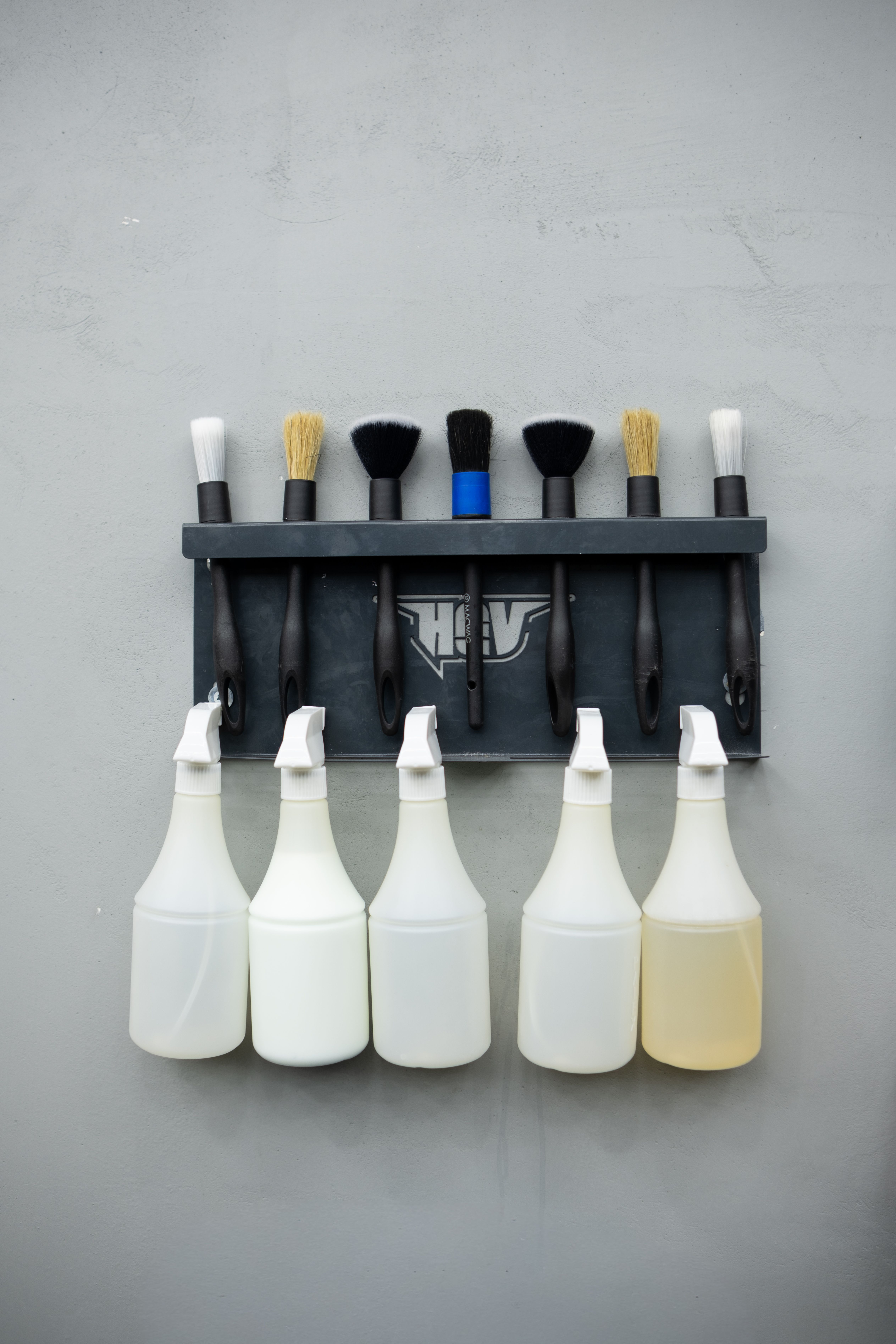 Organized Cleaning Brushes and Bottles on Rack · Free Stock Photo