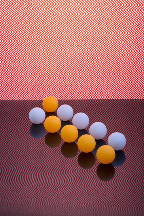 Free Abstract arrangement of ping pong balls on a patterned reflective surface with vibrant zigzag background. Stock Photo