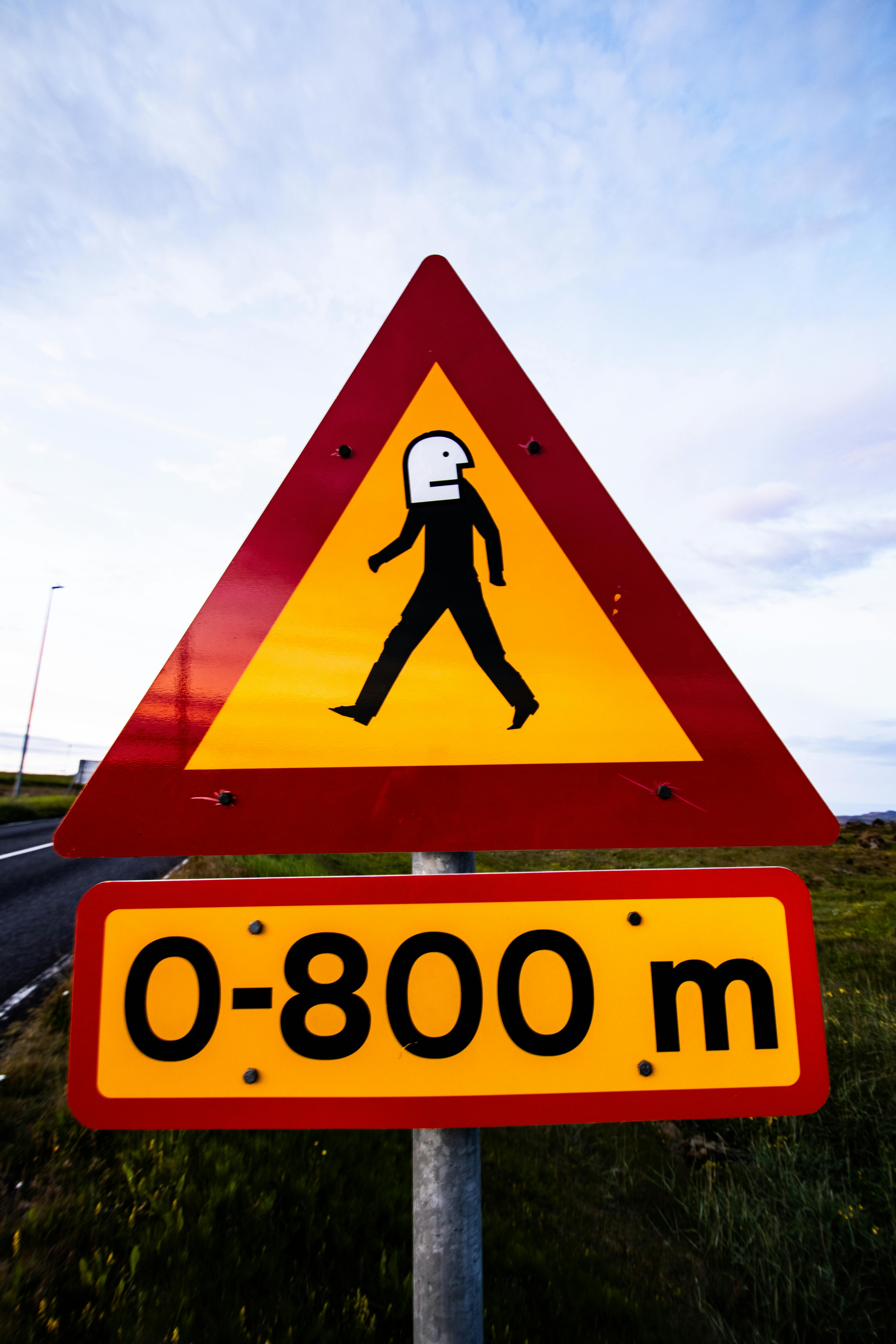 Quirky Icelandic road sign featuring abstract pedestrian design, captured in a scenic outdoor setting.