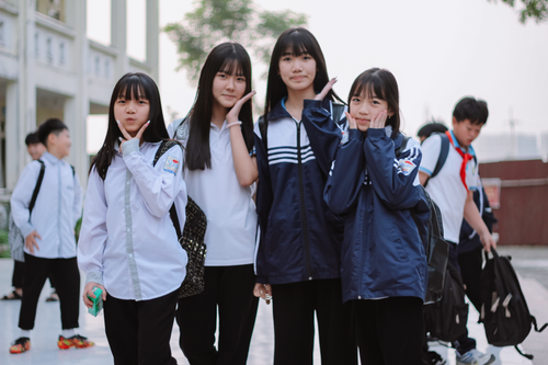 Free Asian students smiling and posing outdoors in school uniforms. Bright day. Stock Photo