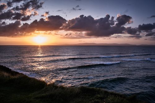Free Beautiful sunset over the Atlantic Ocean at Bundoran, Ireland with dramatic clouds and calm waves. Stock Photo