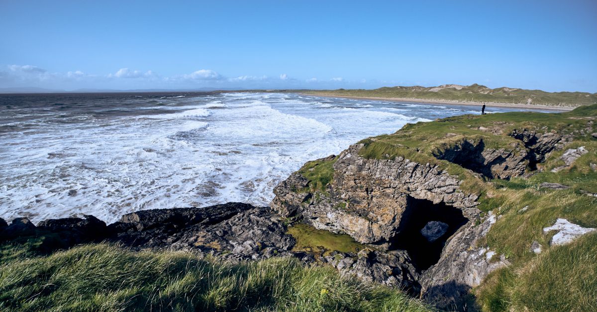 Scenic view of Bundoran's rugged coastline with waves and natural arch in Donegal, Ireland.