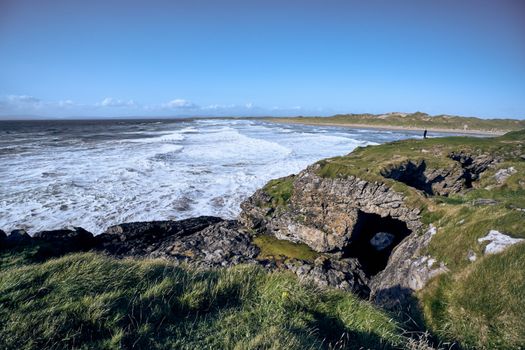 Scenic view of Bundoran's rugged coastline with waves and natural arch in Donegal, Ireland.