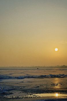 A tranquil winter sunset over a frozen landscape in Konaev, Kazakhstan, capturing the beauty of icy tranquility.