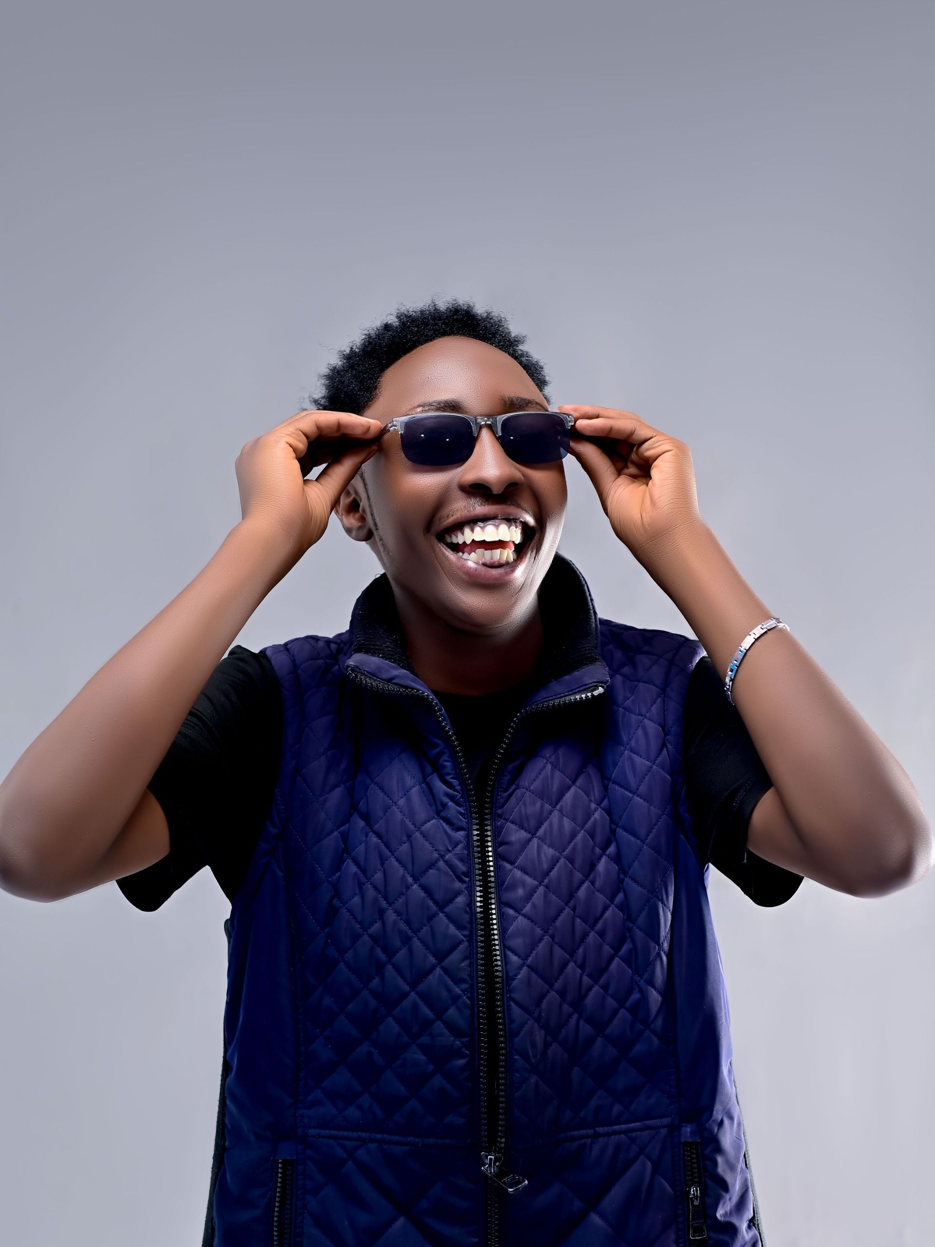 Cheerful person wearing sunglasses and a blue vest, showing a joyful expression.