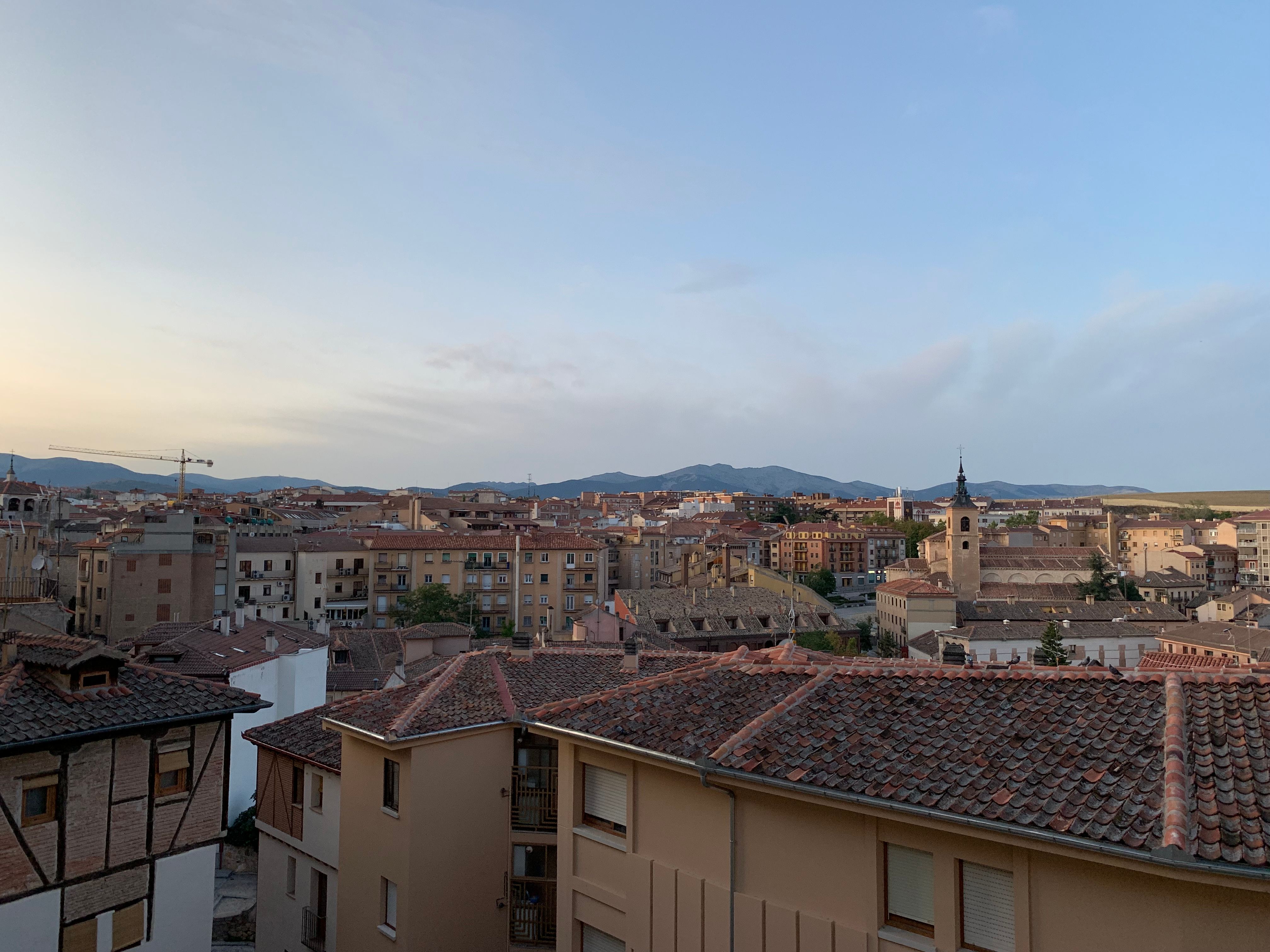 Stunning sunset view of Segovia skyline with historic architecture and mountains in the background.