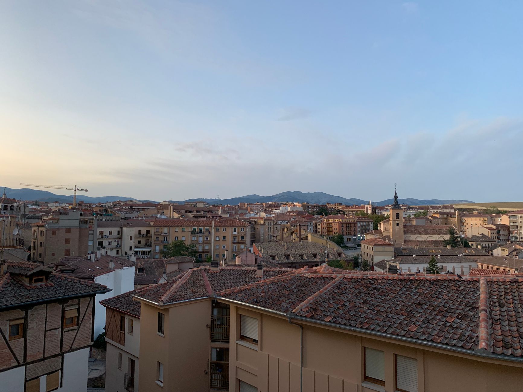 Stunning sunset view of Segovia skyline with historic architecture and mountains in the background.