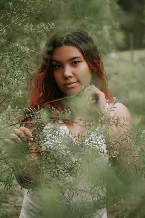 Free Captivating portrait of a woman standing amidst lush greenery, exuding natural beauty. Stock Photo