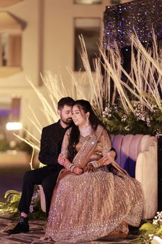 Elegant couple embracing on a decorative couch during a celebration.