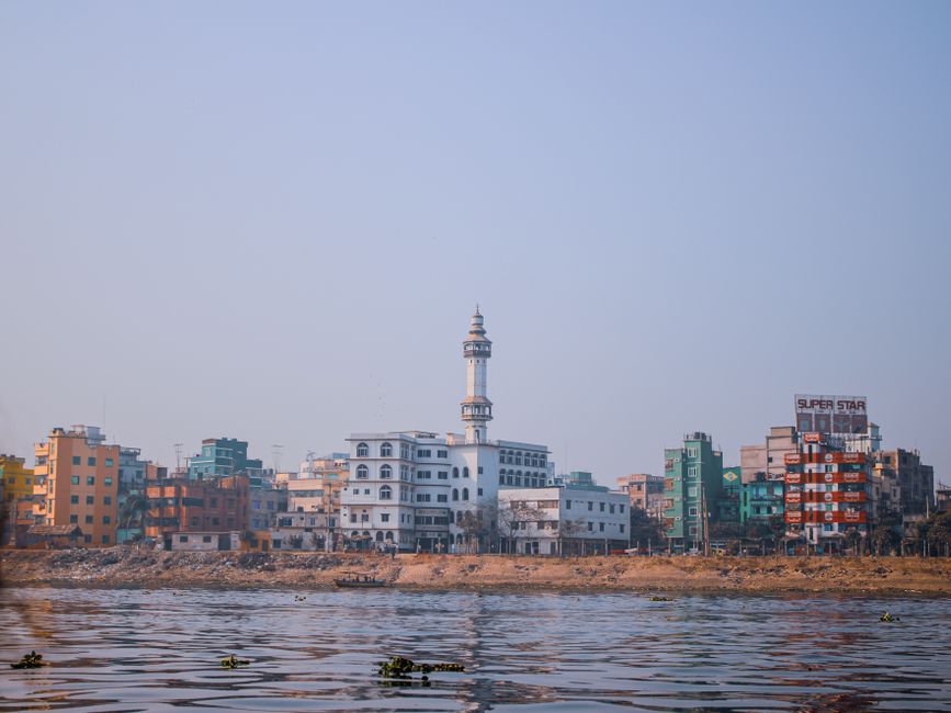 View of colorful buildings and mosque along riverbank in Dhaka, Bangladesh.
