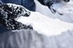 A hand in a black winter glove holding a slab of snow