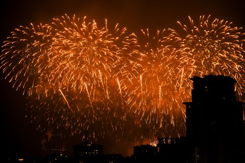 Free Vibrant fireworks illuminating the night sky over city buildings in a dazzling display. Stock Photo
