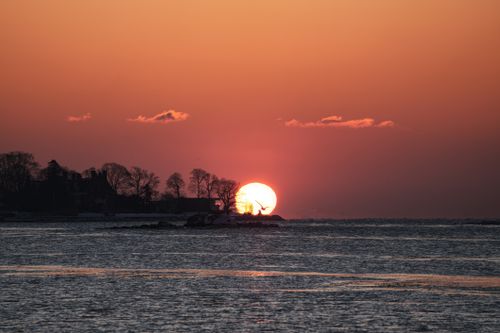Free Beautiful sunset with silhouette of trees and calm water, capturing a peaceful moment. Stock Photo