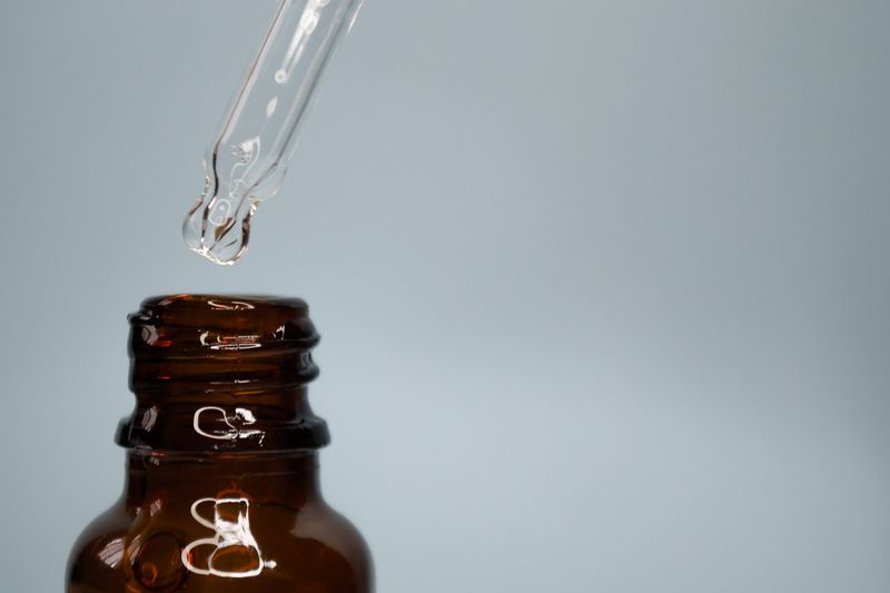 Close-up of a glass dropper with an amber bottle against a neutral background.