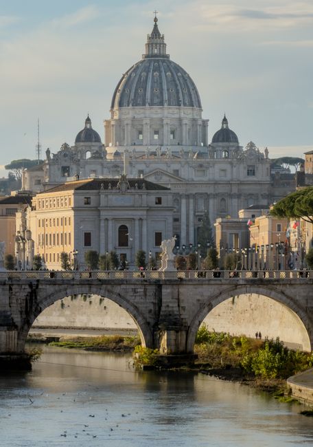A stunning view of St. Peter's Basilica and the Tiber River in Rome, Italy, captured during the day.